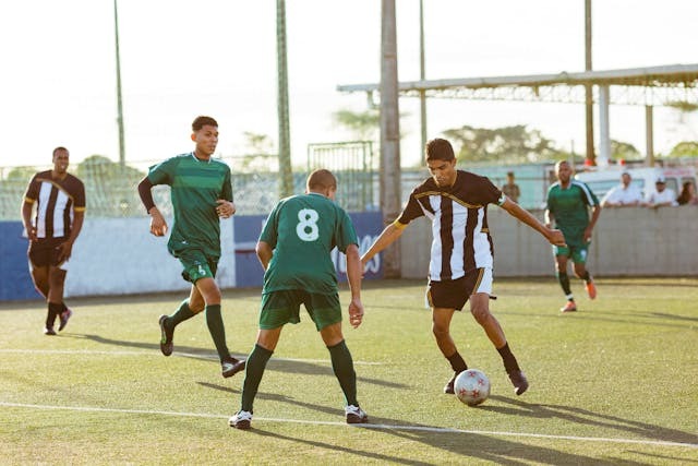 Five soccer players in action during a daytime soccer match