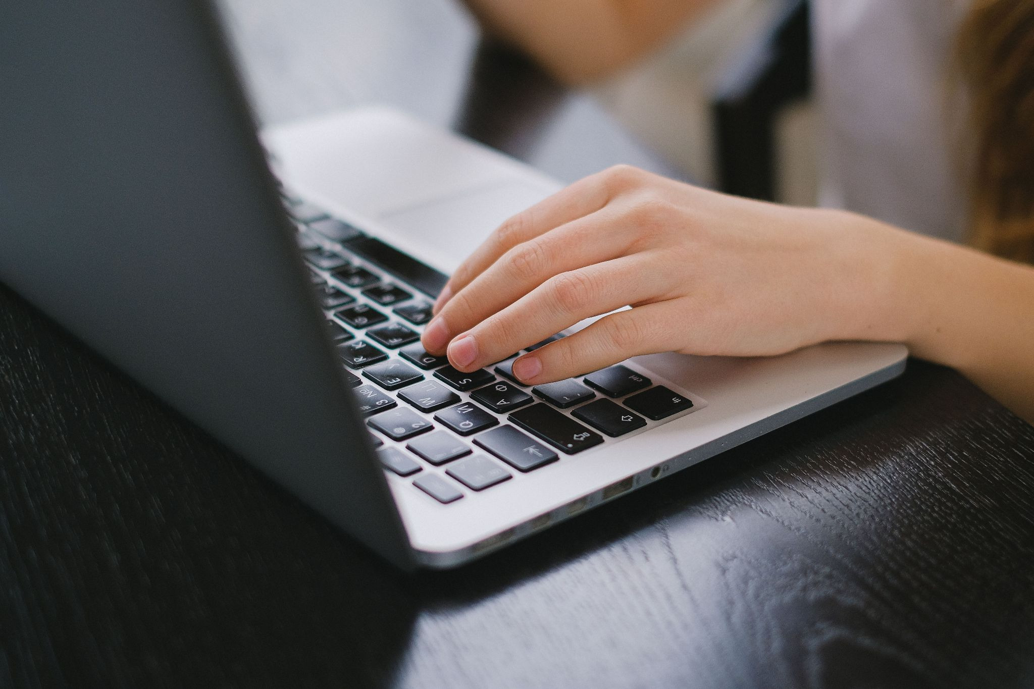 Close-up of a hand typing a Petersburg rental property listing on a laptop on a wooden desk