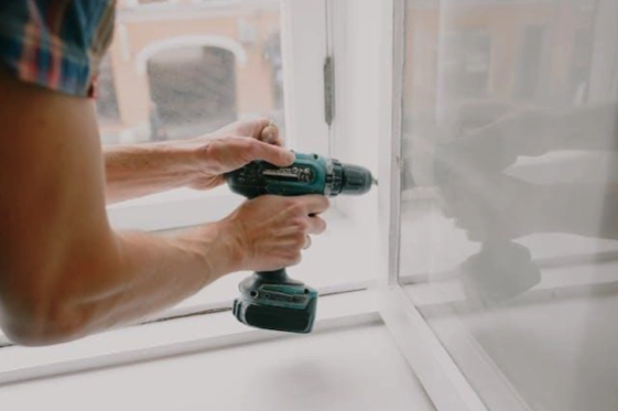 A person using a drill to fix a door.